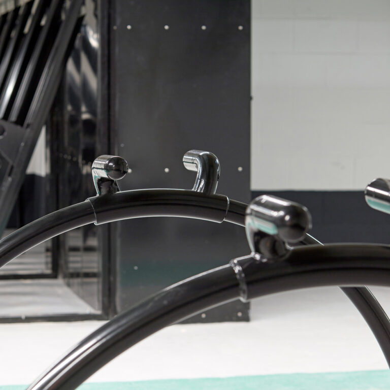 Jet-black powder coated Equilibrium Cycle Stands with vertical locker and semi vertical racks in the background